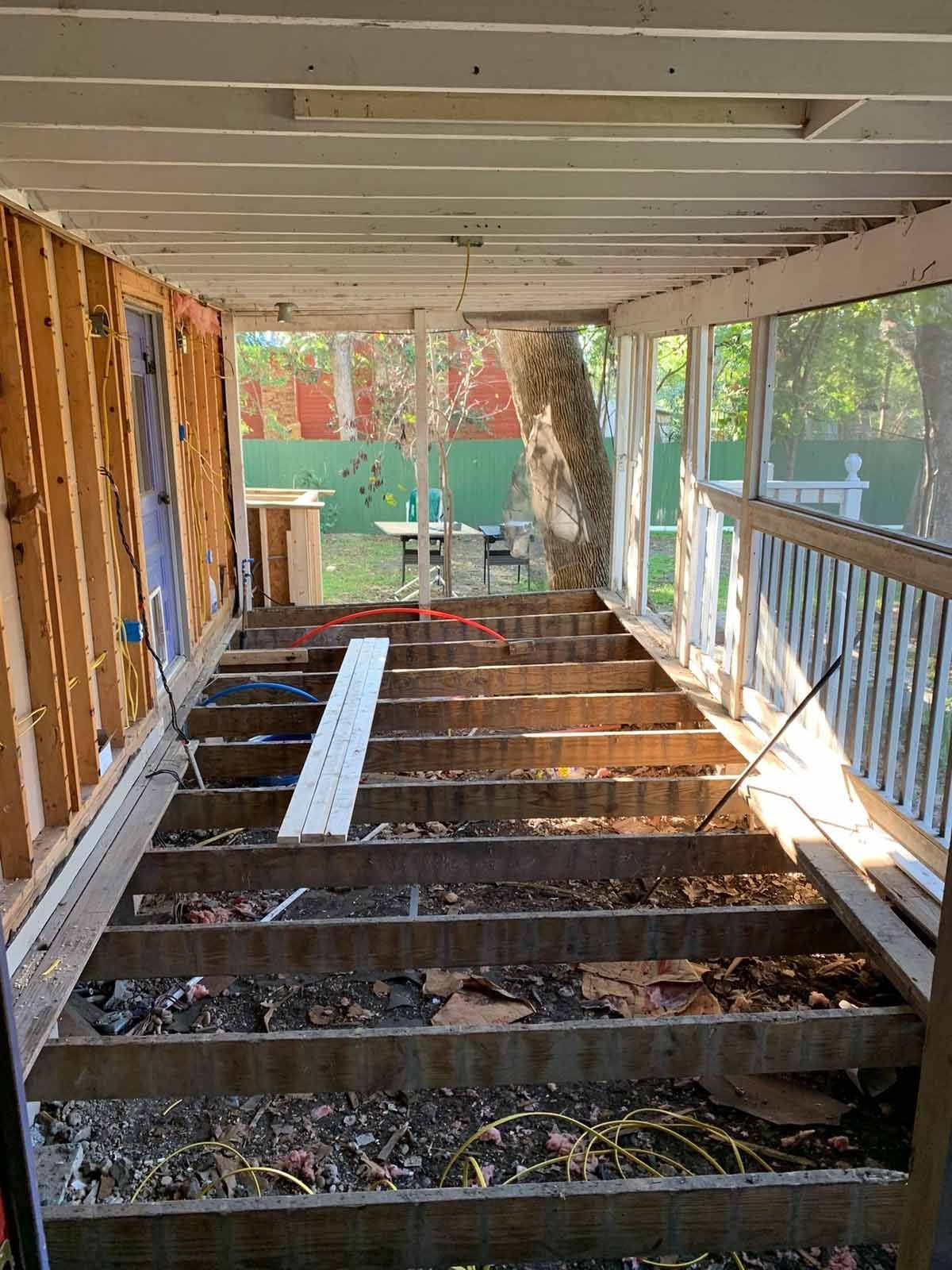 Sunroom under renovation with exposed floor joists and framing.