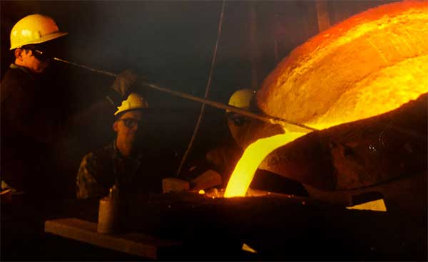 A group of men are pouring molten metal into a furnace.