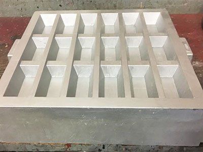 A metal tray with holes in it is sitting on top of a wooden table.