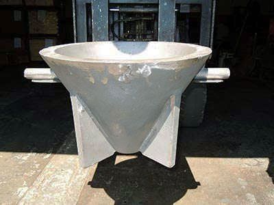 A large concrete bowl is sitting on a table next to a forklift.
