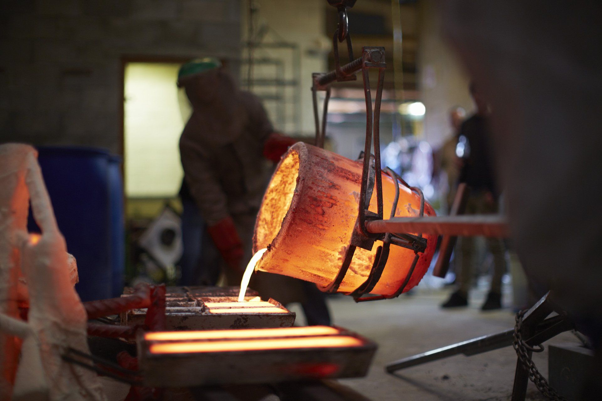 A man is pouring molten metal into a furnace in a factory.