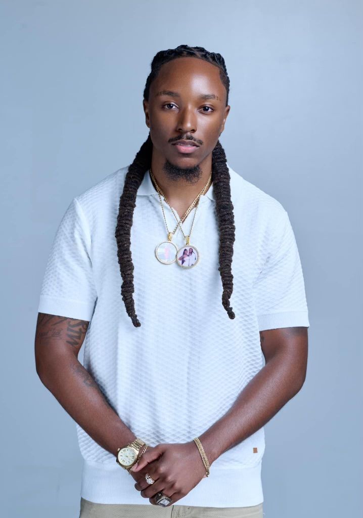 A woman is sitting at a desk with a laptop and a vase of flowers.