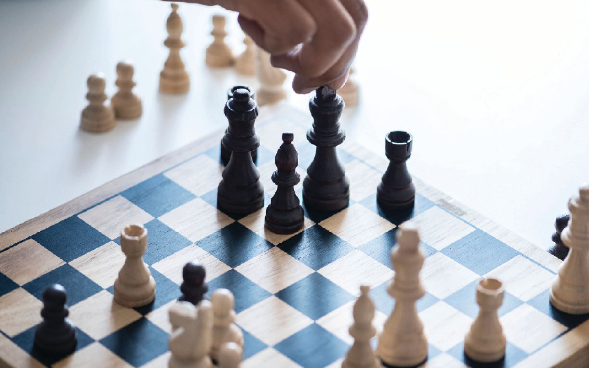 A person is playing a game of chess on a wooden chess board.