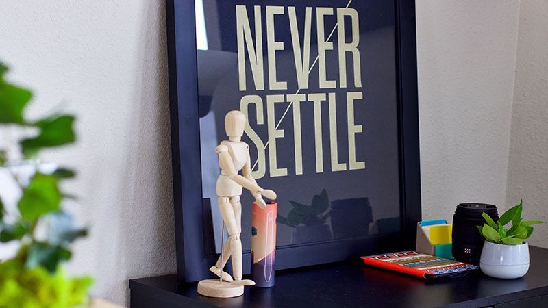 A framed poster that says `` never settle '' is hanging on a wall.