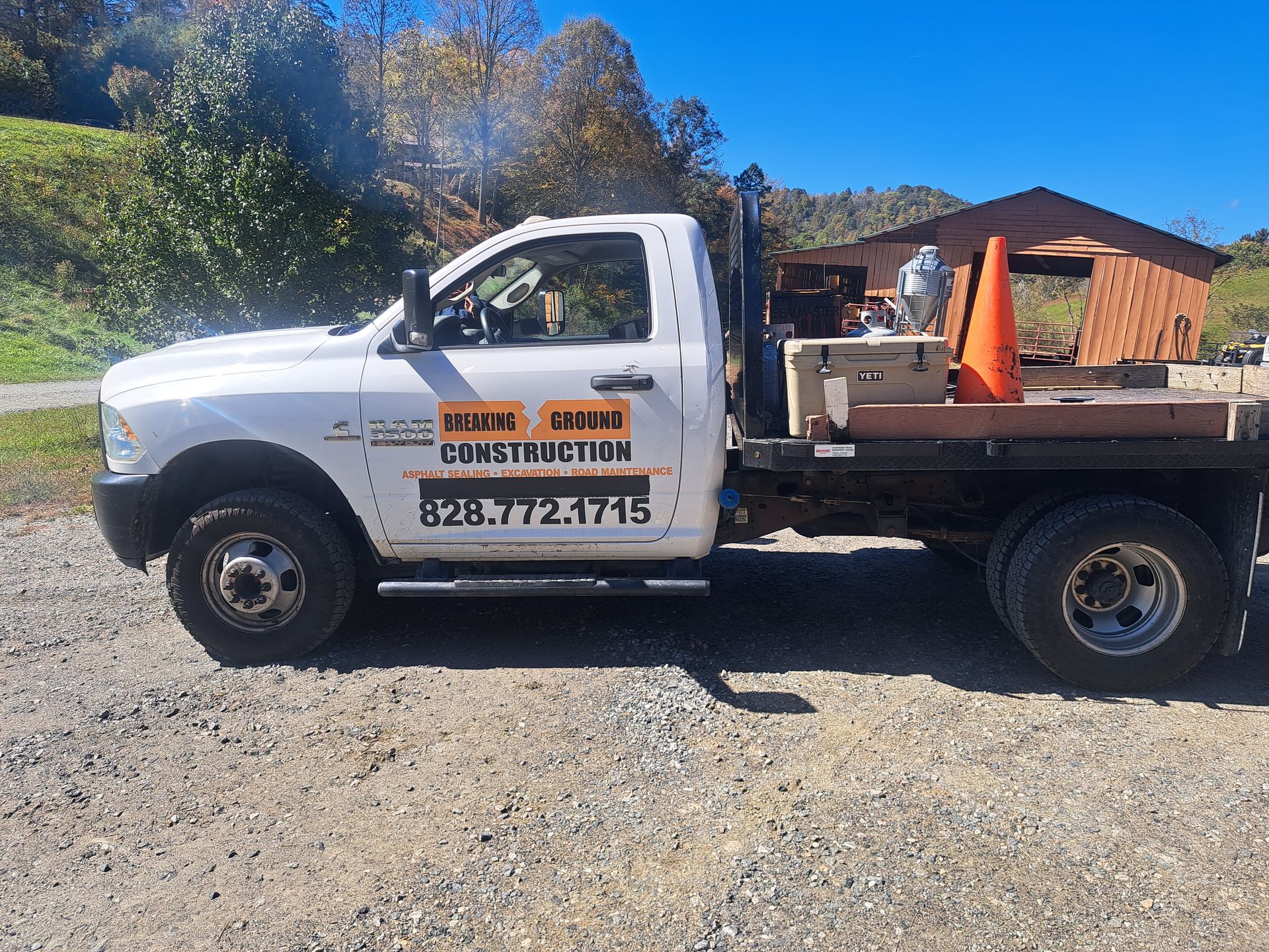 A white construction truck is parked in a gravel lot.