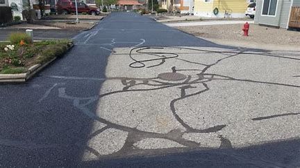 A shadow of a person is cast on the asphalt of a road.