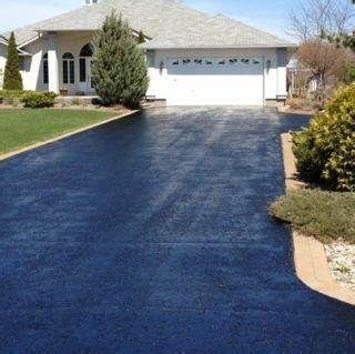 A black driveway leading to a house with a white garage door.