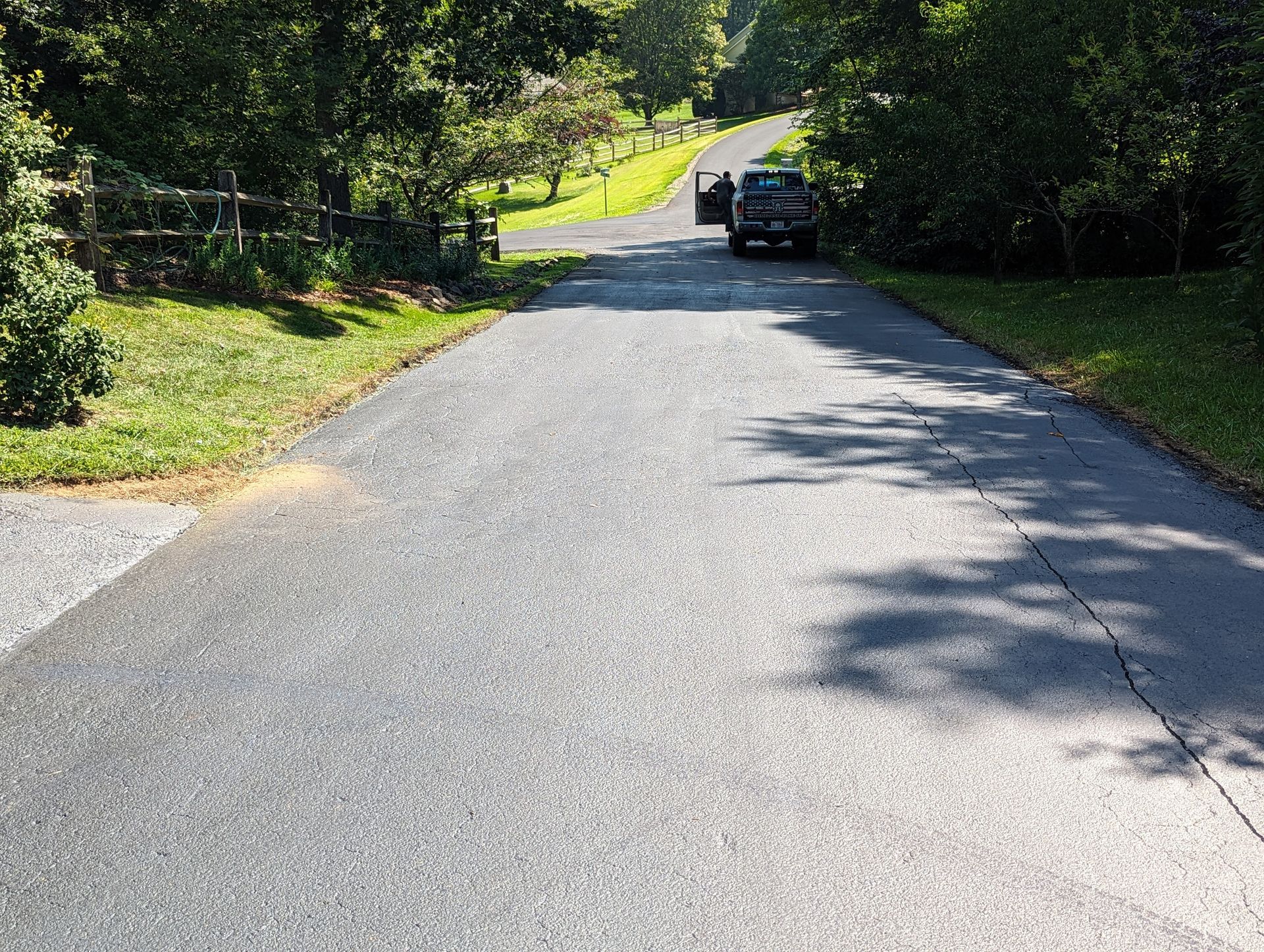 A car is driving down a road next to a fence.