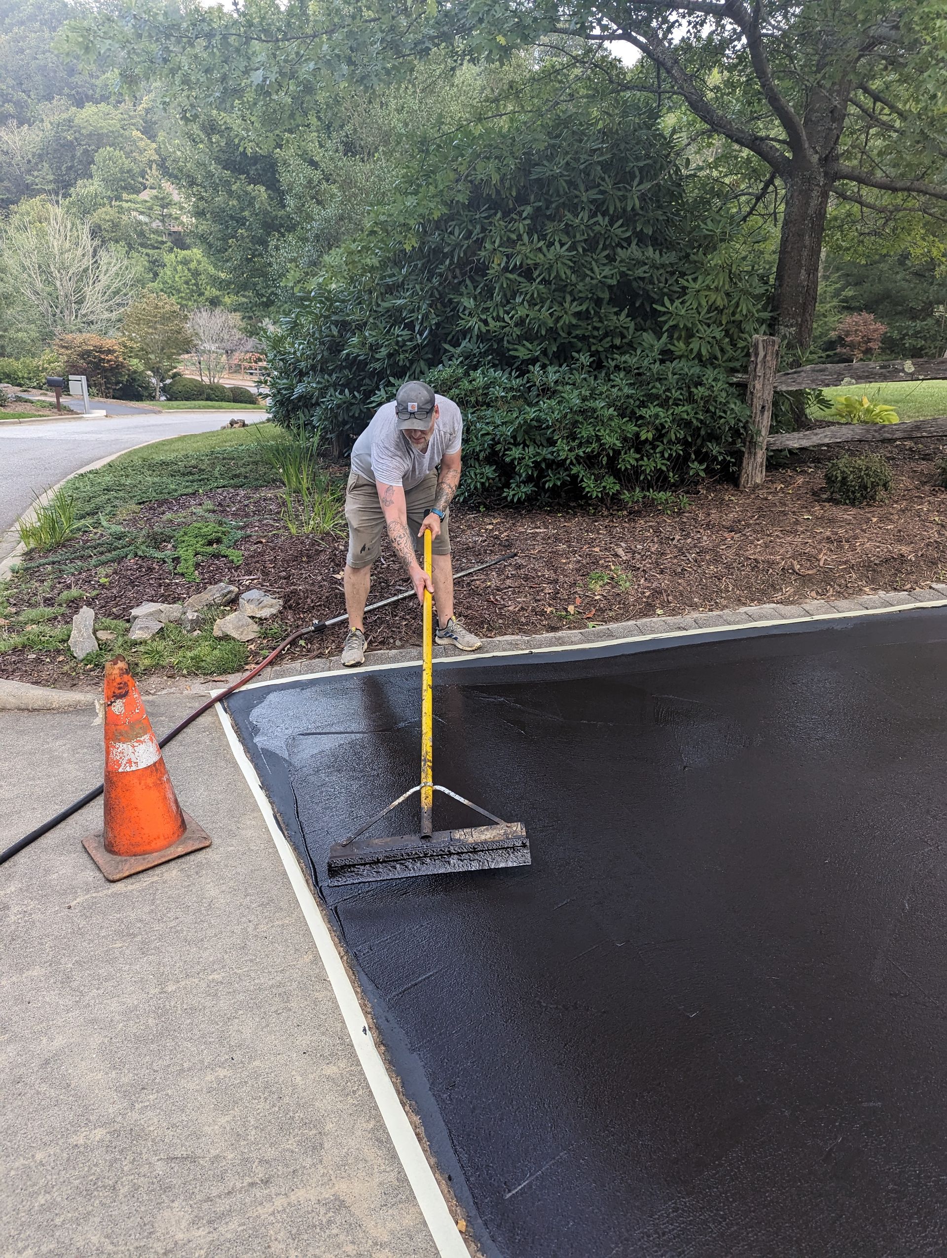 A man is cleaning a parking lot with a broom.