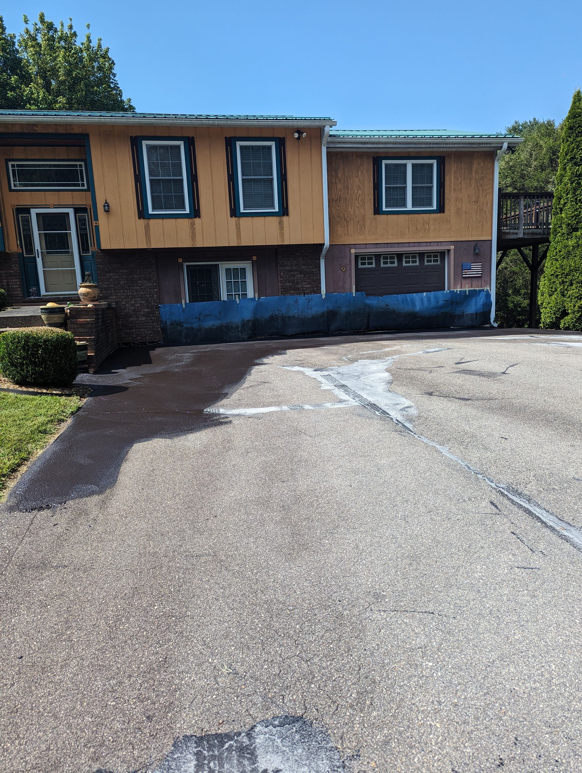 A house with a blue tarp on the driveway is being remodeled.