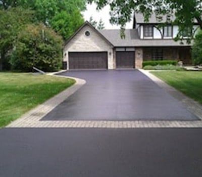 A driveway leading to a house with two garage doors