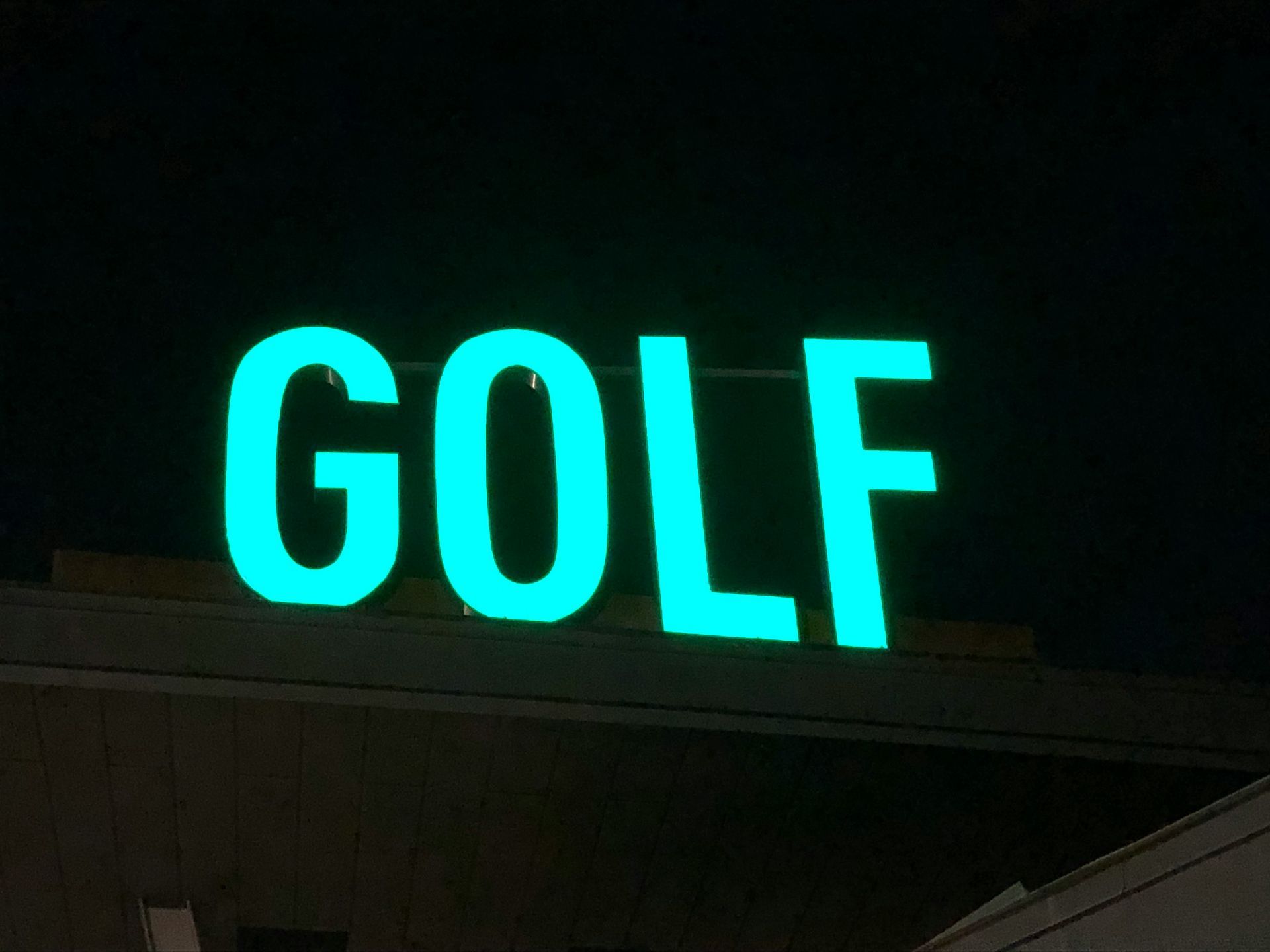 Panneau « GOLF » vert brillant contre un ciel sombre.
