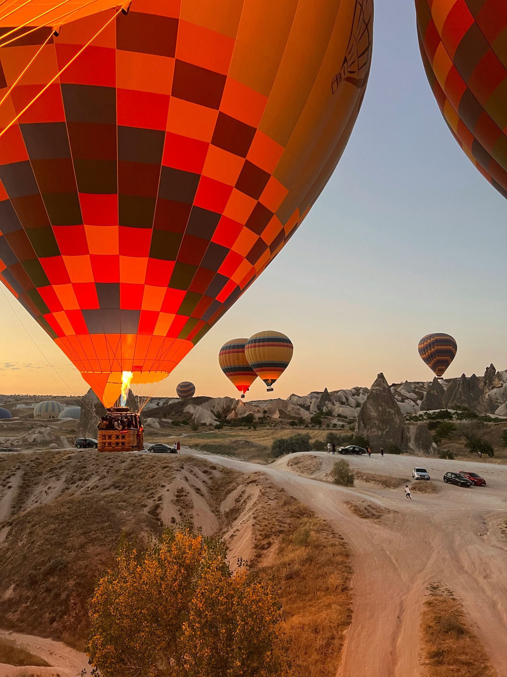Montgolfières s'élevant au lever du soleil au-dessus de la Cappadoce, en Turquie ; teintes orange, rouge et jaune.