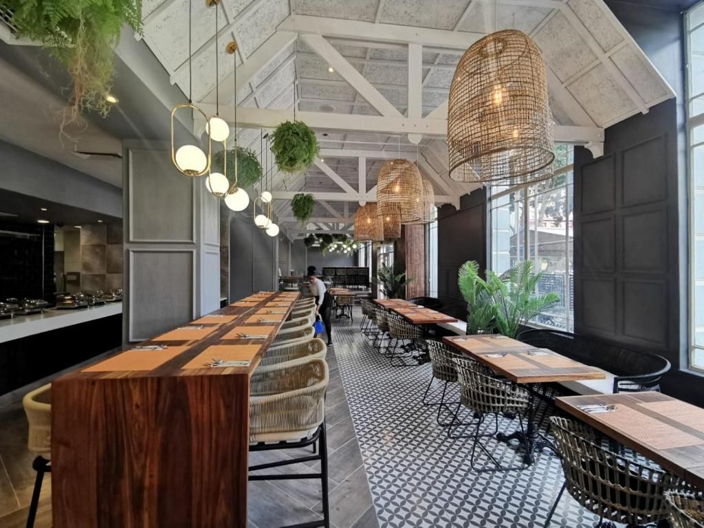 Vue aérienne d'un terrain de golf avec un bâtiment en arrière-plan, près d'un plan d'eau, sous un ciel nuageux.