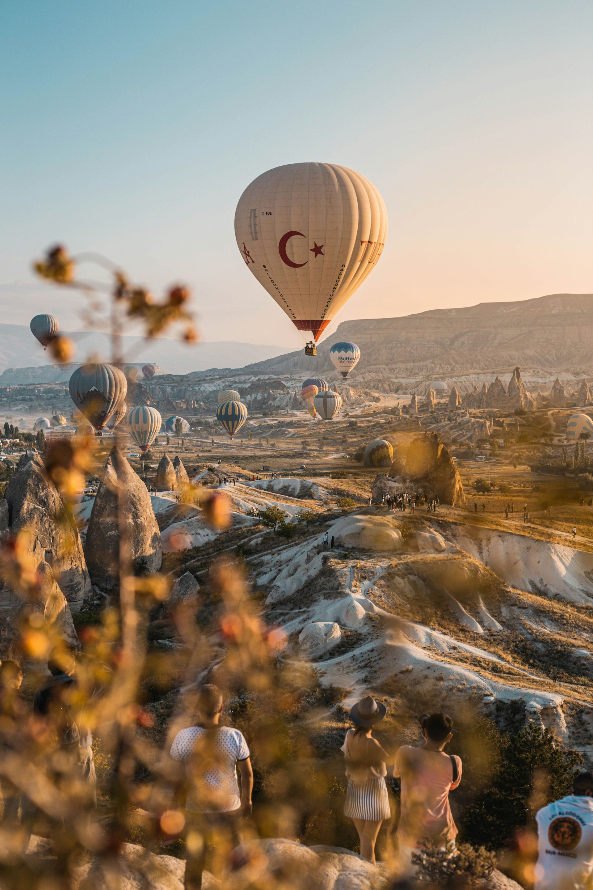 Des montgolfières arborant le drapeau turc s'élèvent au-dessus du paysage de Cappadoce, sous le regard des spectateurs.