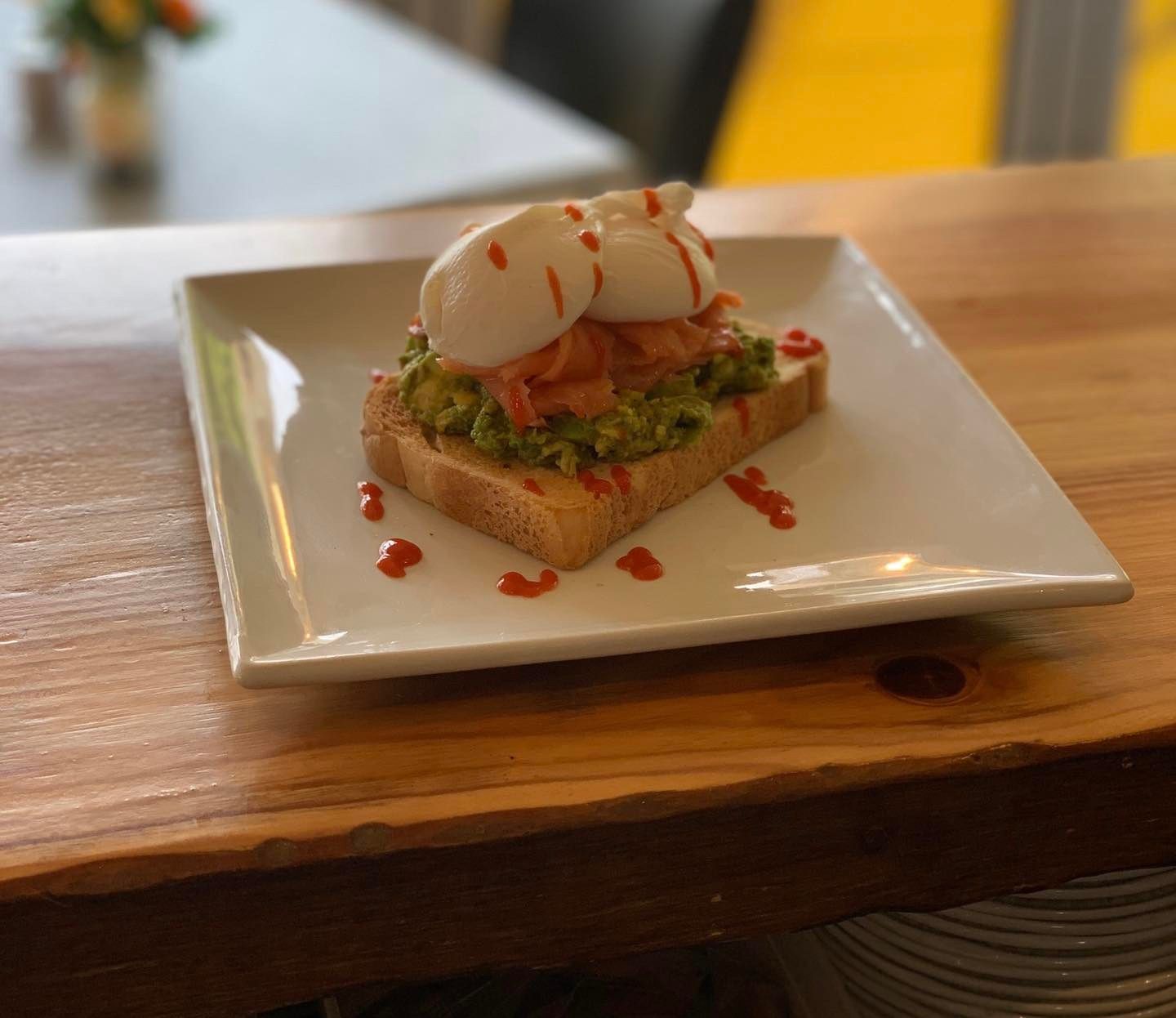 A sandwich with avocado and poached eggs on a white plate