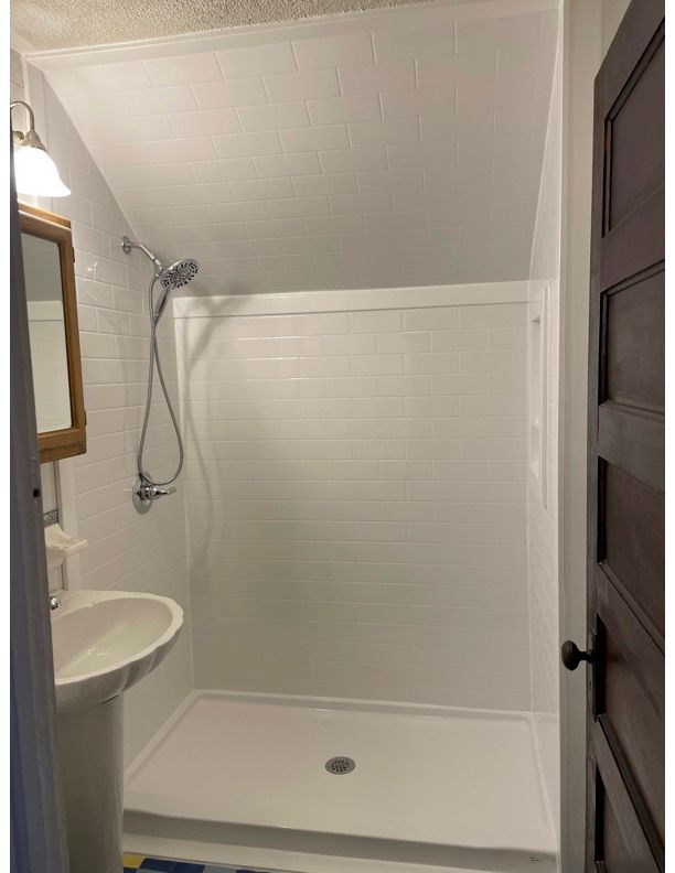 A bathroom with a shower stall and a window.