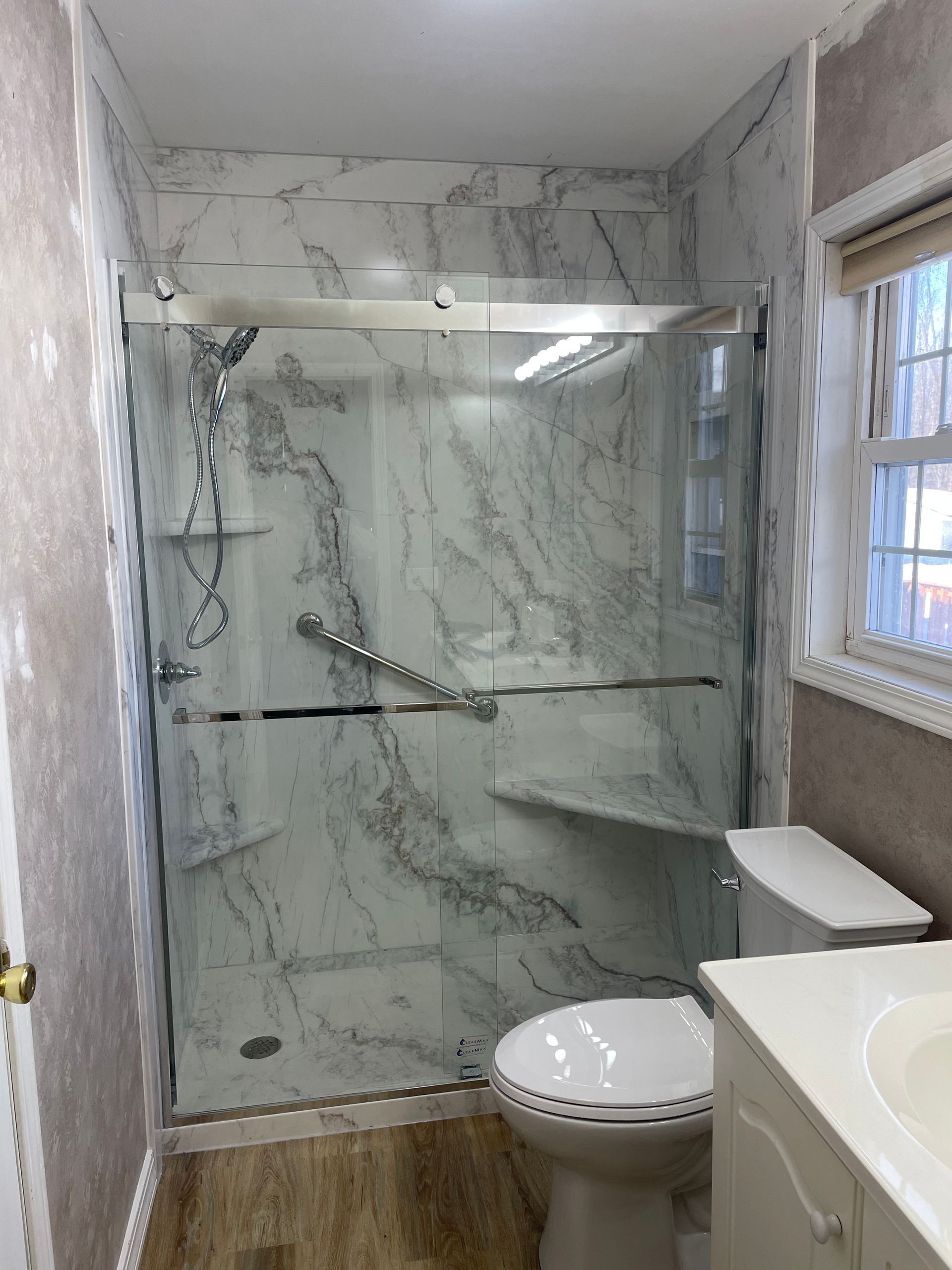 A bathroom with a toilet , sink and shower stall.