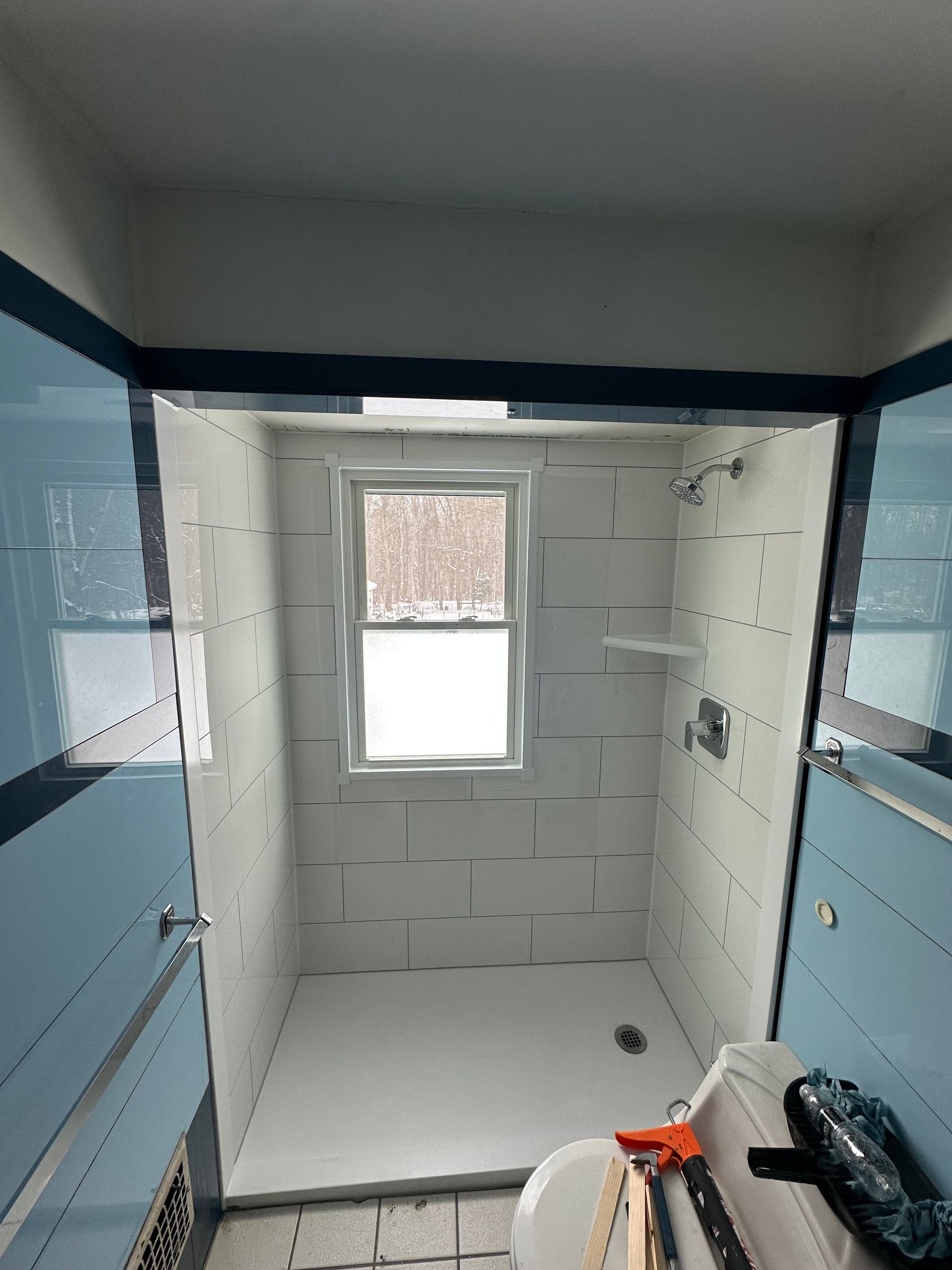 A bathroom with a shower stall and a window.