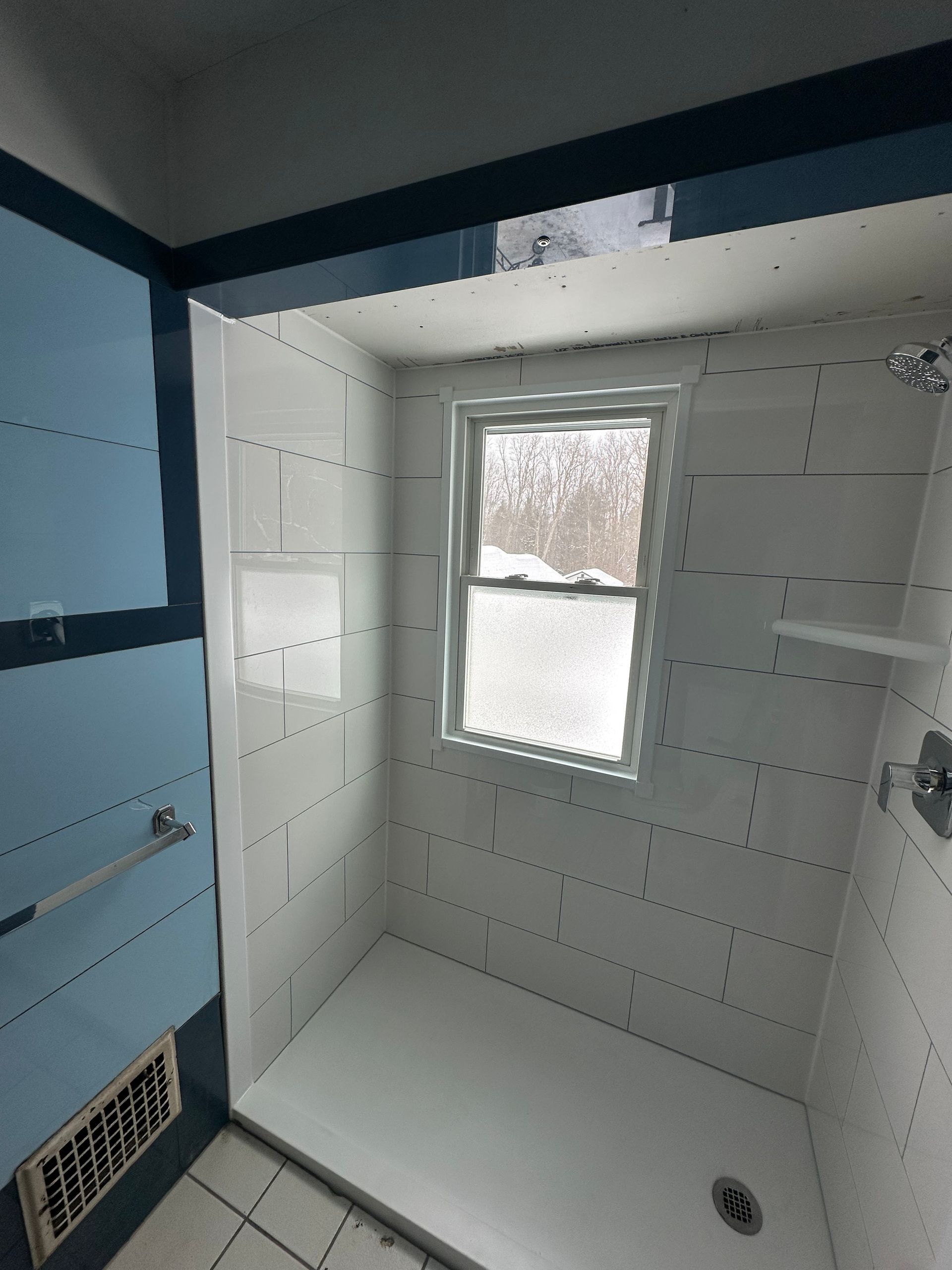 A bathroom with a walk in shower and a window.