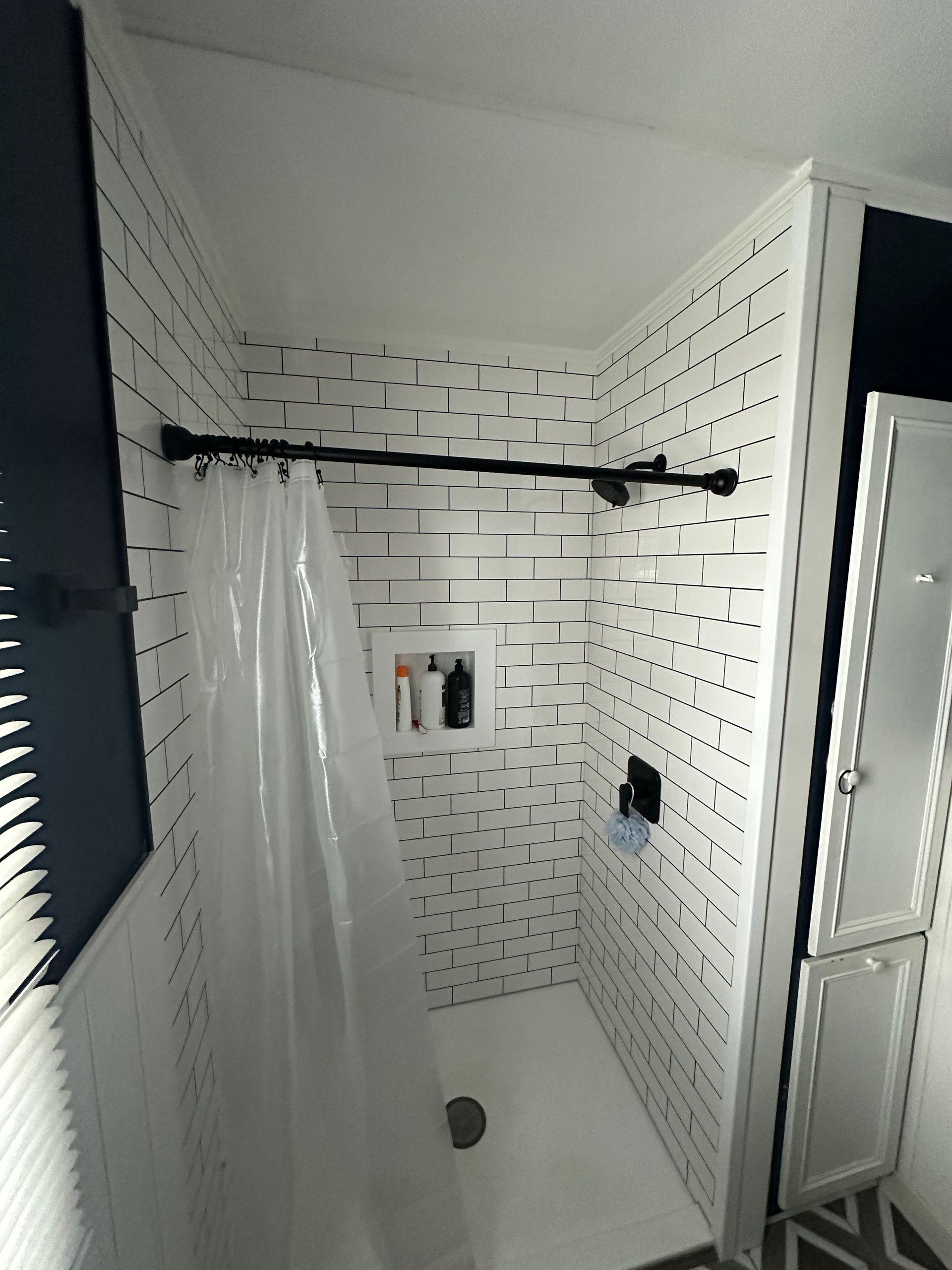 A bathroom with white tiles and a shower curtain