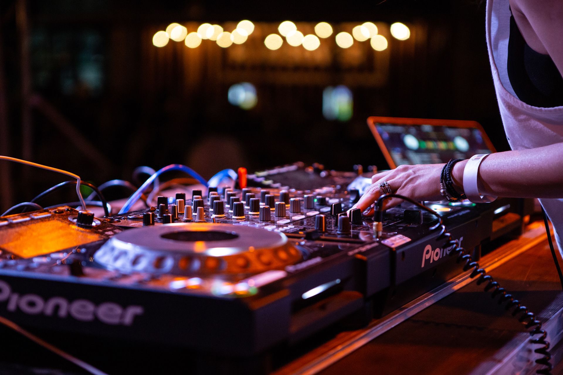 DJ mixing music on a Pioneer console at a nighttime venue.