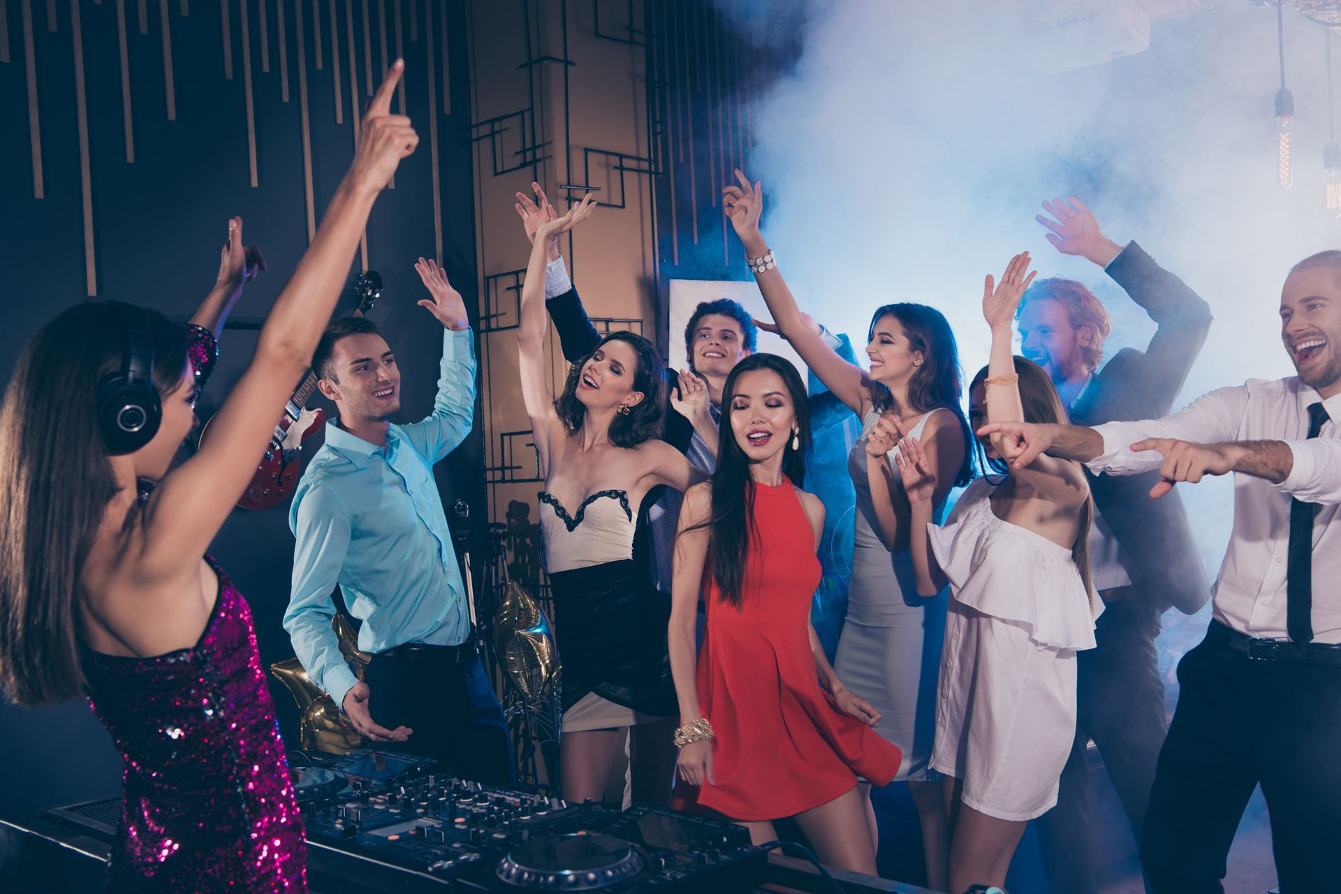 People dancing enthusiastically in a club with colorful lights and smoke.