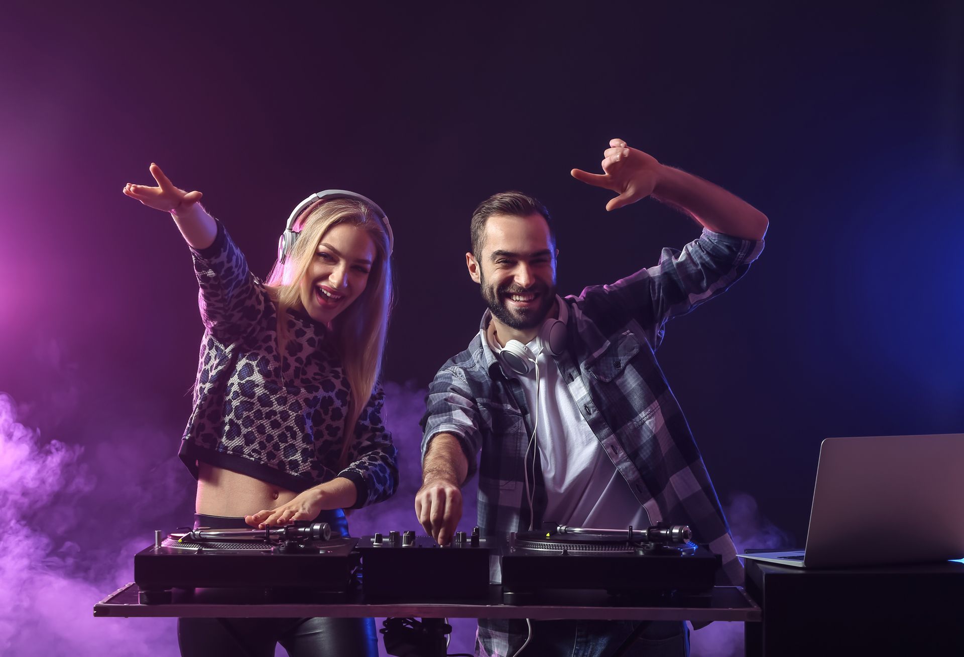 A DJ duo at a club, mixing music. 