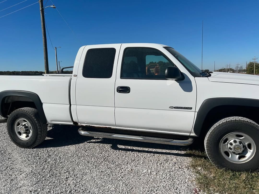 White extended cab pickup truck parked outdoors on gravel.