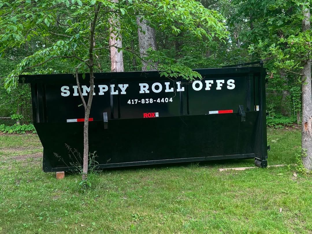 Black dumpster in a grassy area, with 