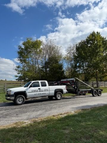 White pickup truck with trailer on a paved road, trees in the background under a blue sky.
