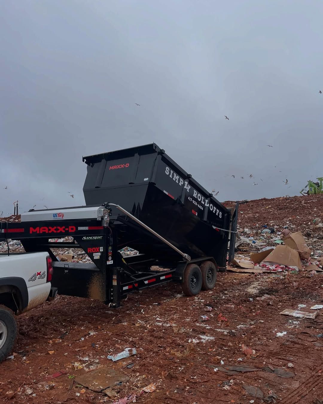 A dumpster is being towed by a truck in a dumpster.