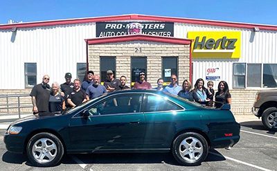 A group of people standing around a green car in front of a hertz store.