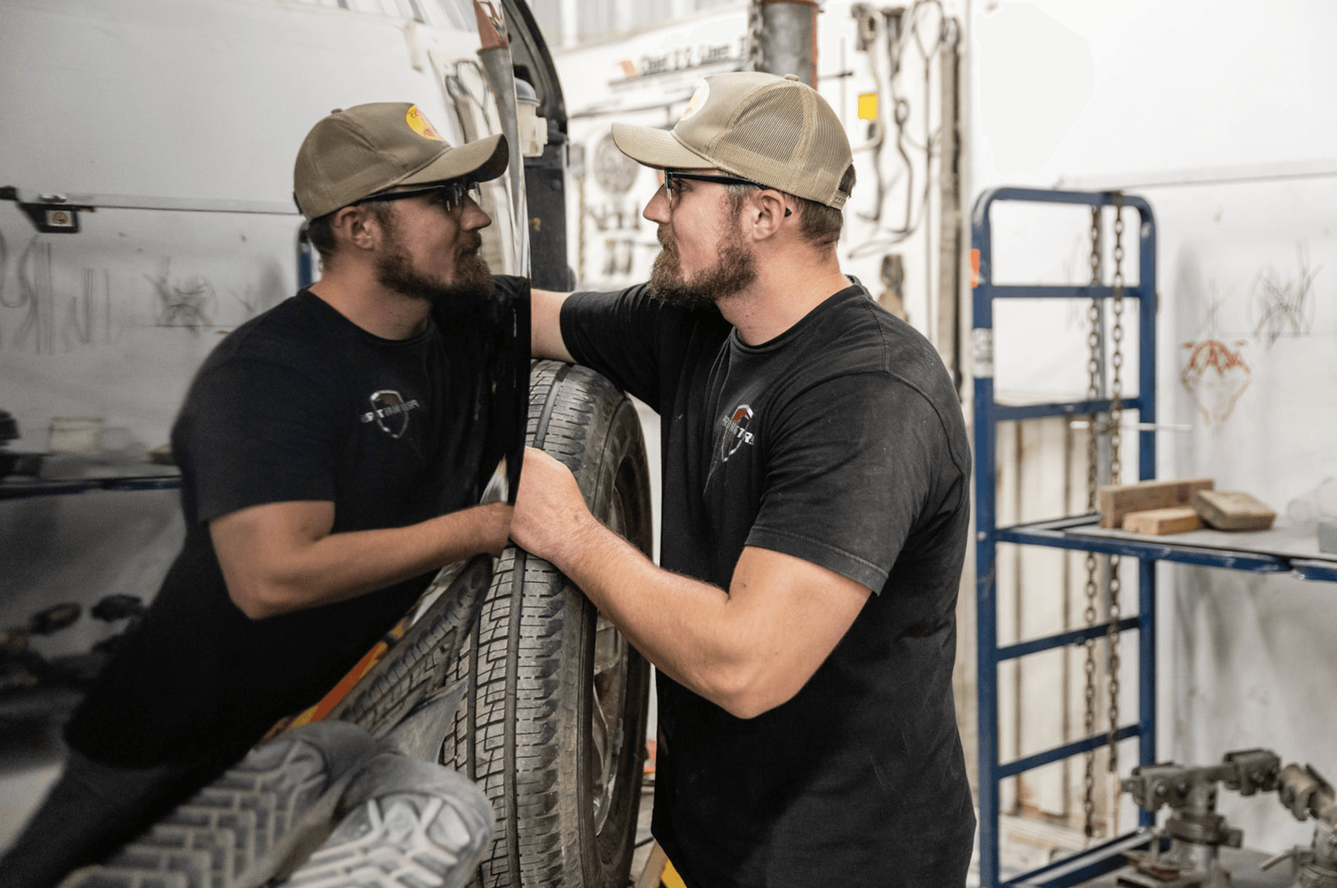 Two men are working on a truck in a garage.