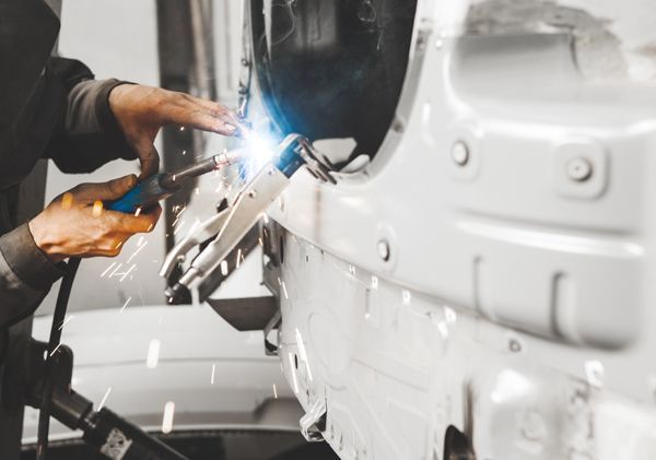 A man is welding a car in a garage.