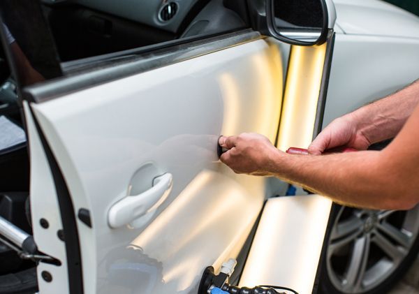 A person is repairing a car door with a light.