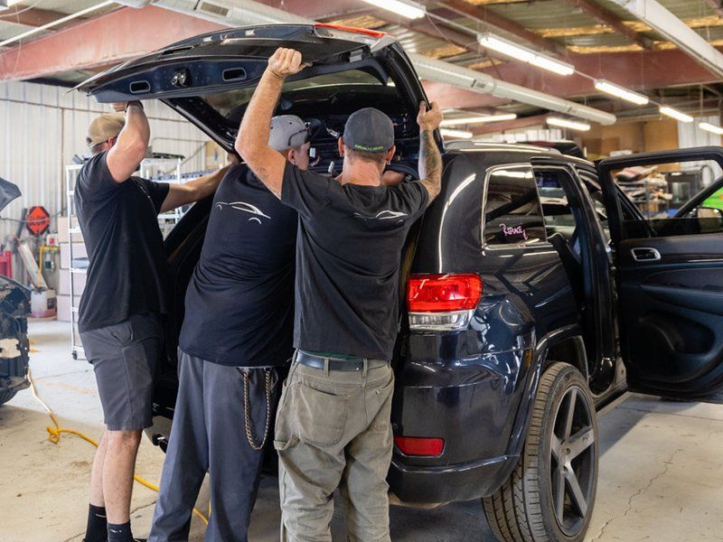 A group of men are working on a car in a garage.