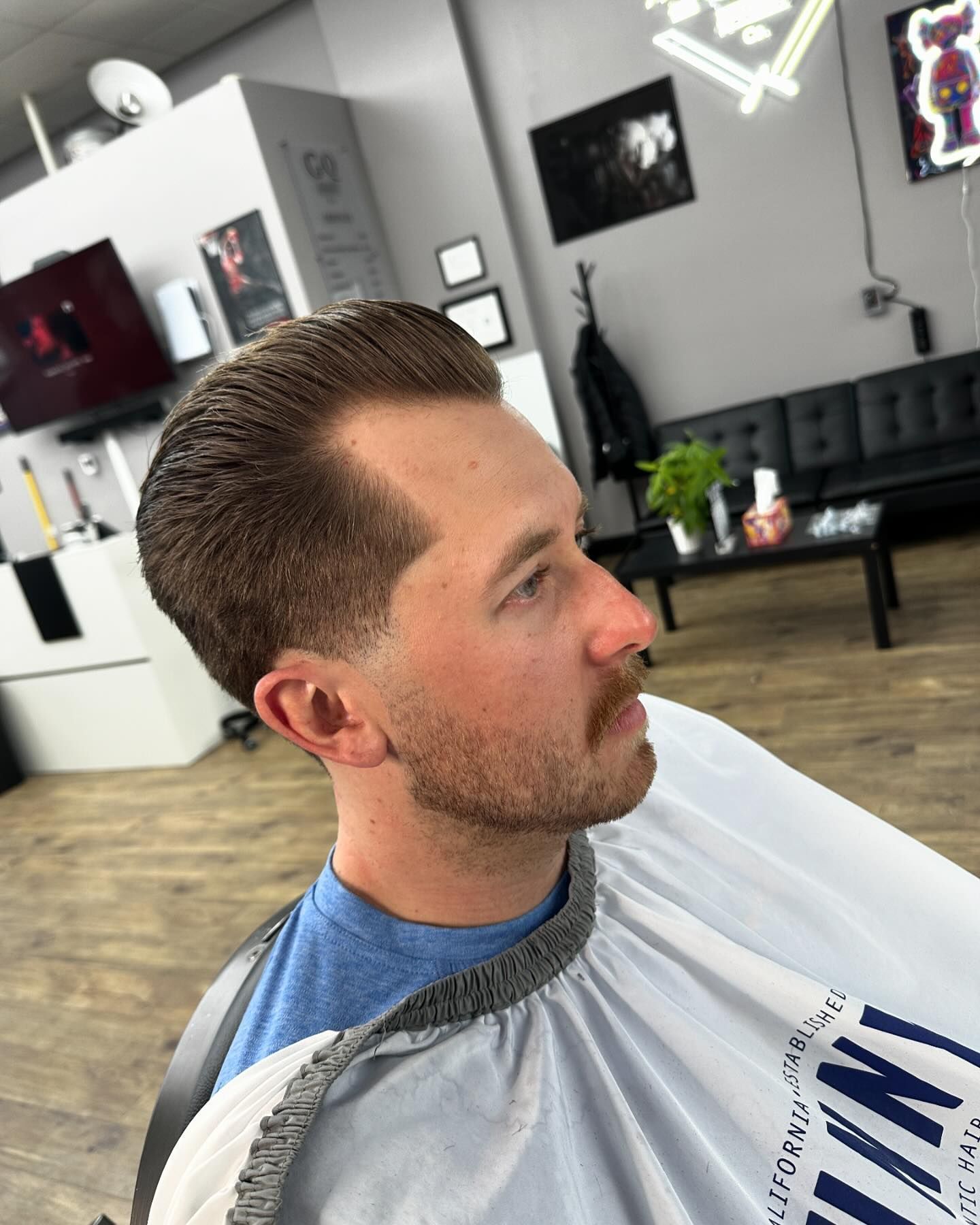 A man is getting his hair cut at a barber shop.
