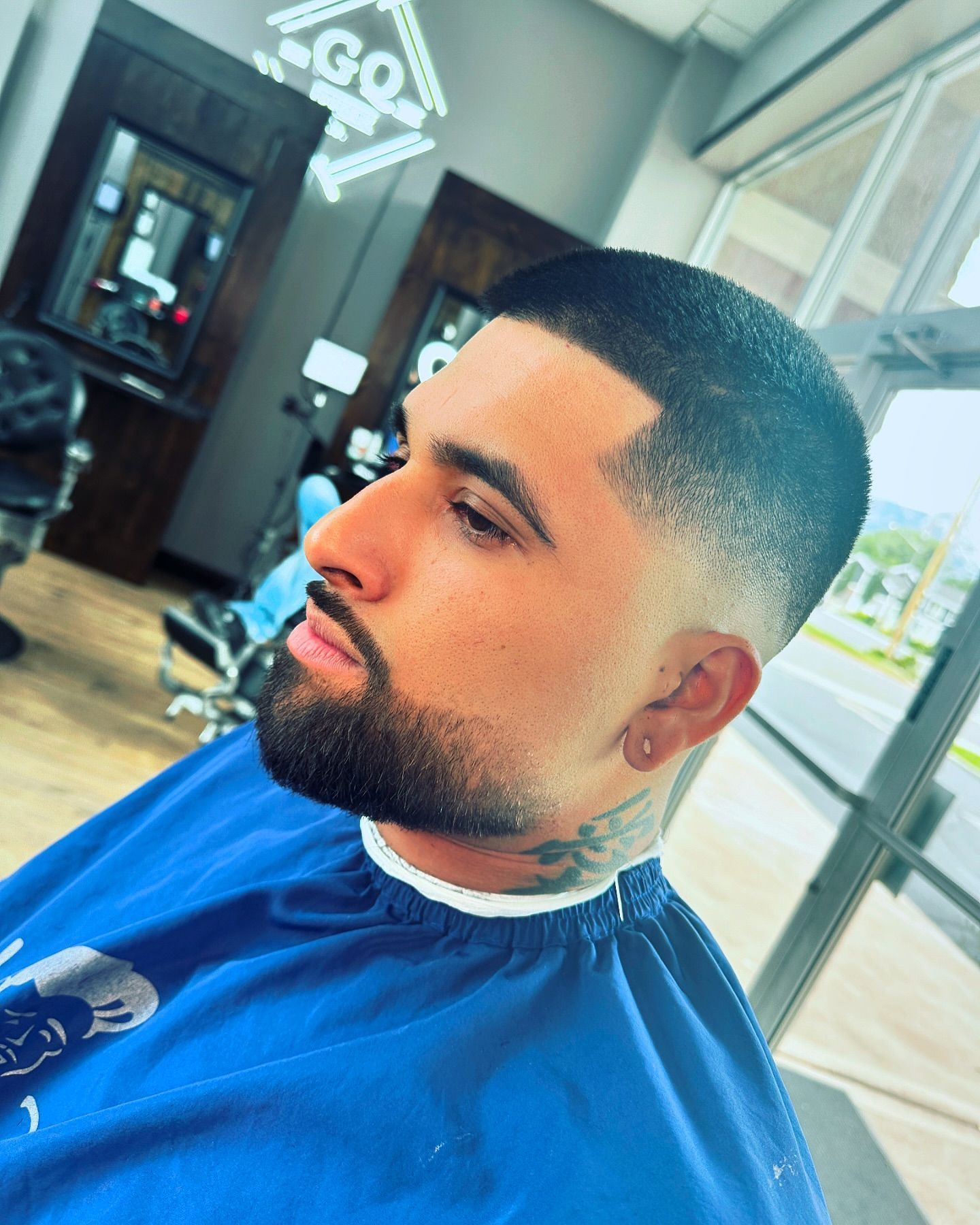 A man with a beard is getting his hair cut at a barber shop