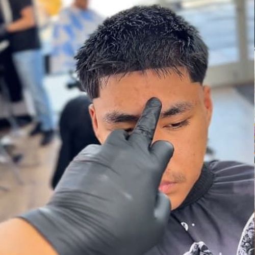 Man with fresh haircut; barber points finger on his forehead; black gloves.