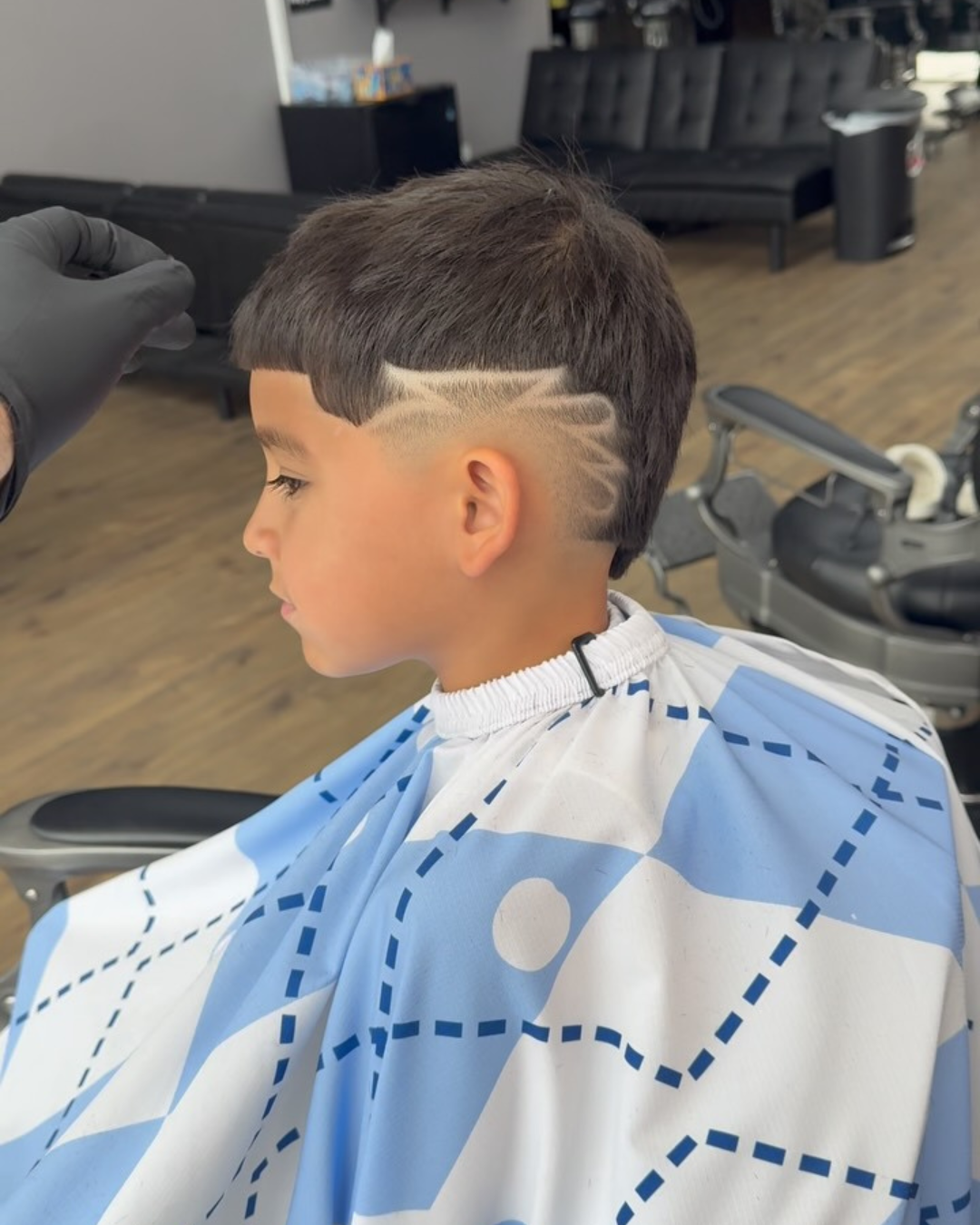 A man is getting his hair cut by a barber wearing a red cape that says johnny b.