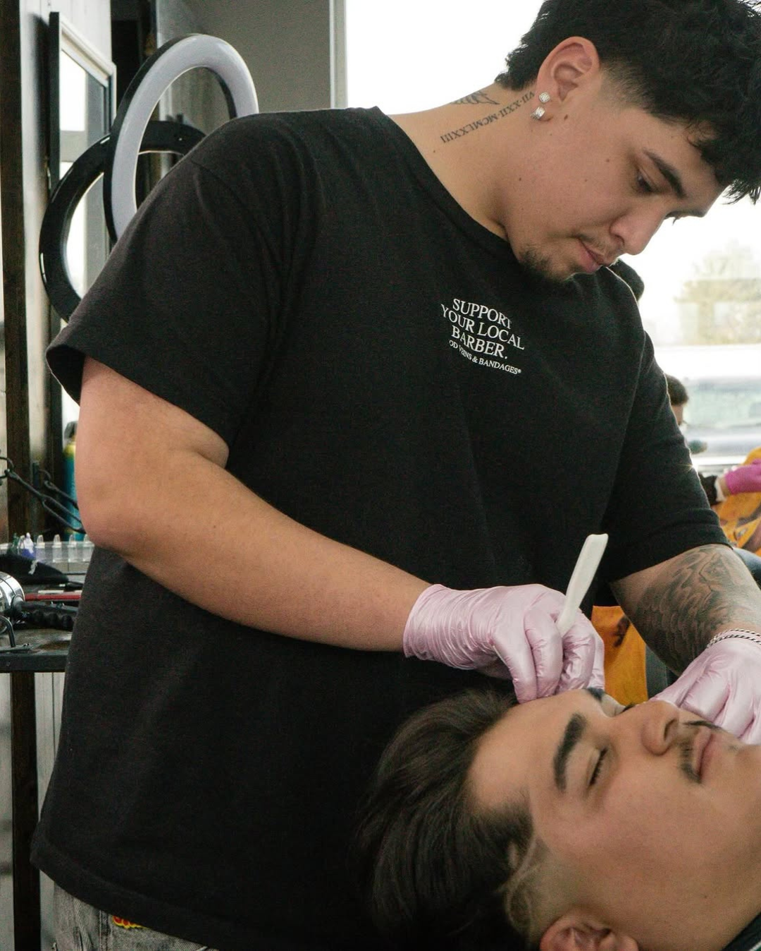A man with a beard is getting his hair cut at a barber shop.