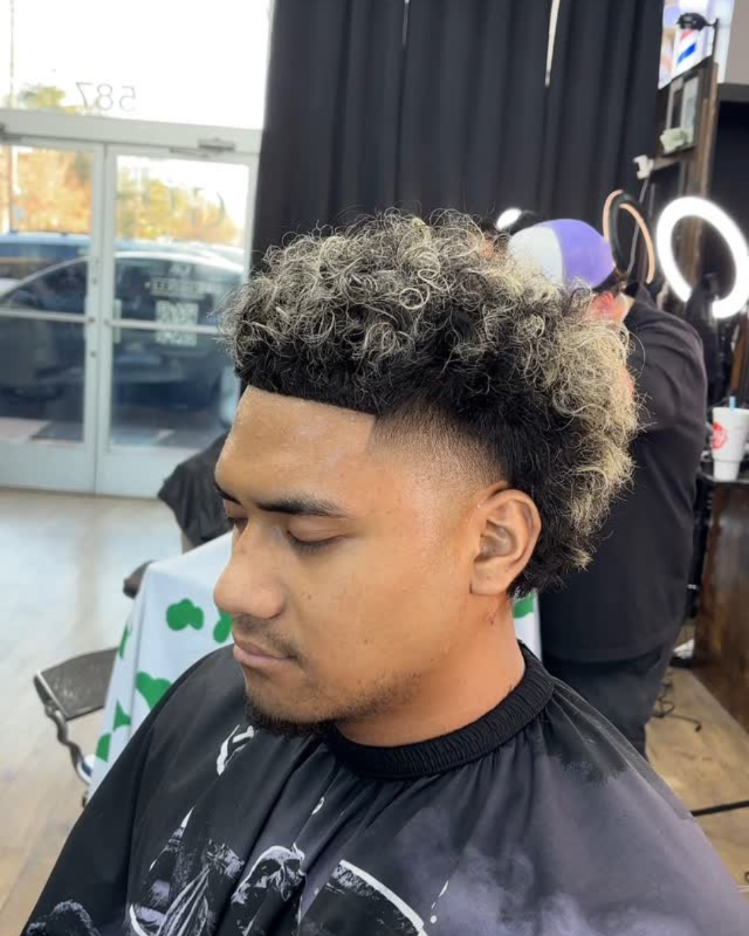 A young boy is getting his hair cut at a barber shop.