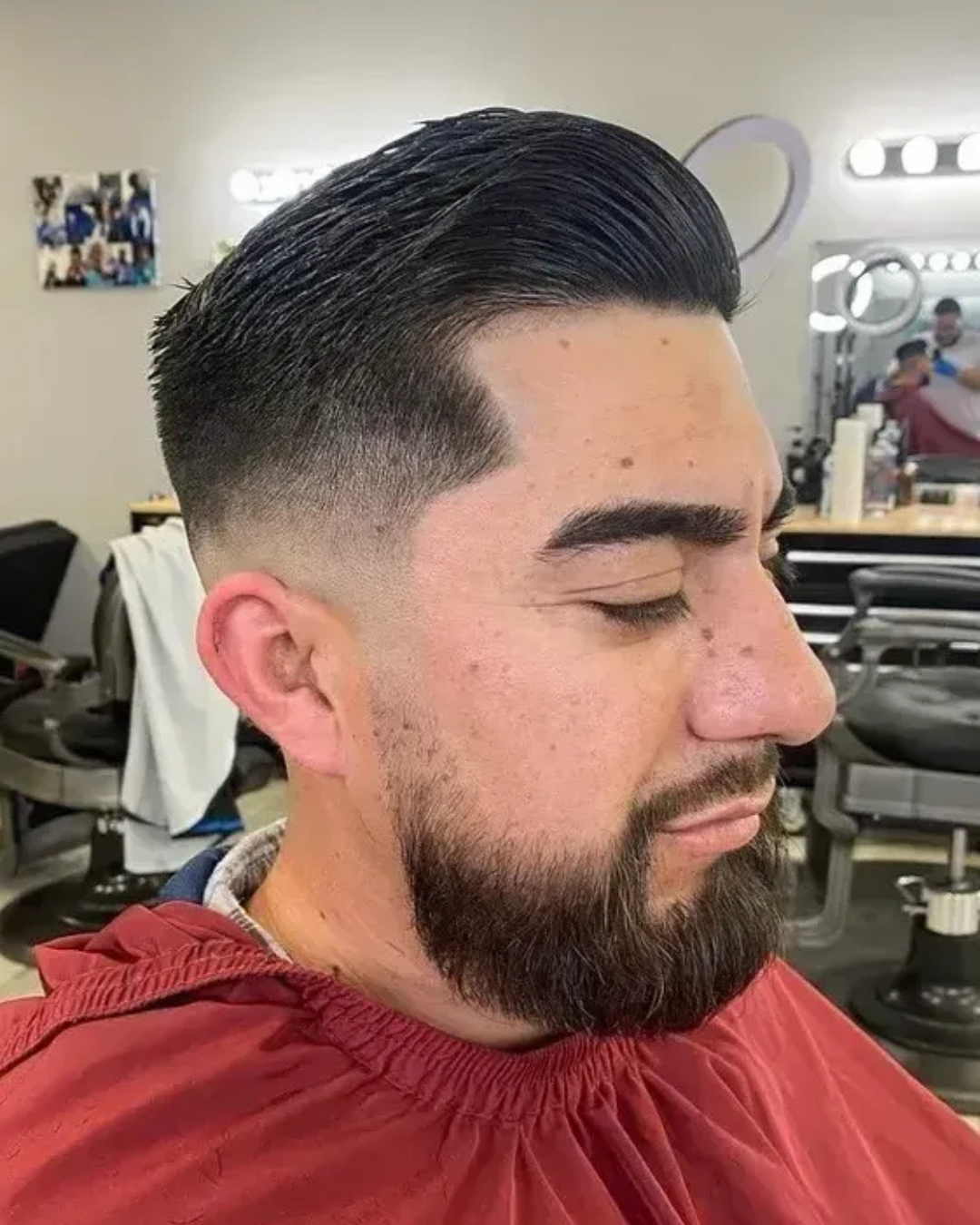 A man with a beard is getting his hair cut at a barber shop.