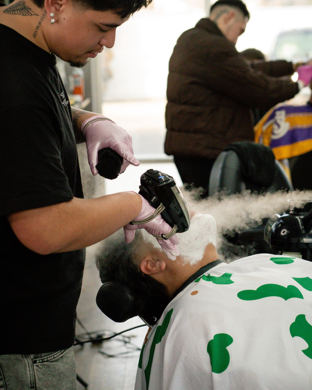 A man in a brown jacket is blow drying a woman 's hair.