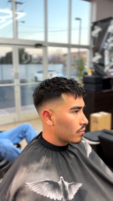 Man with a faded haircut in a barbershop, wearing a cape.