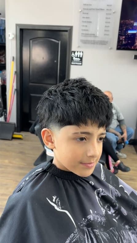 Boy with textured haircut, low fade on sides, at barber shop.