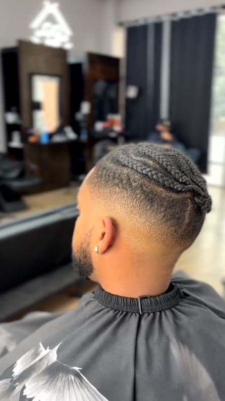 Man getting a fade haircut with braided hair. Barbershop setting.