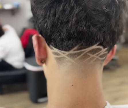 A person's nape with a fade and intricate shaved hair design.