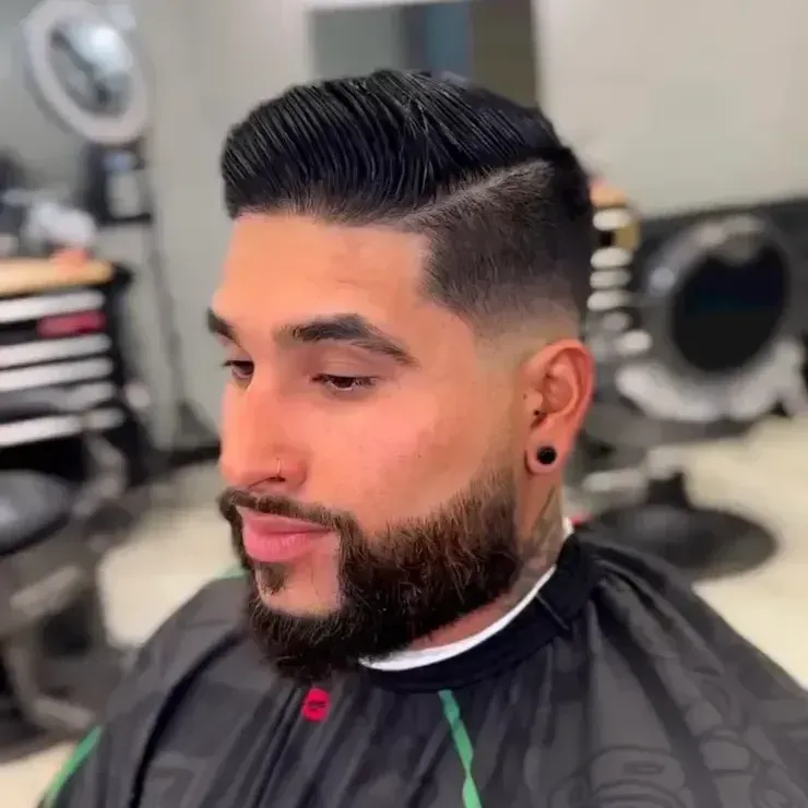 A man with a beard is getting his hair cut at a barber shop.